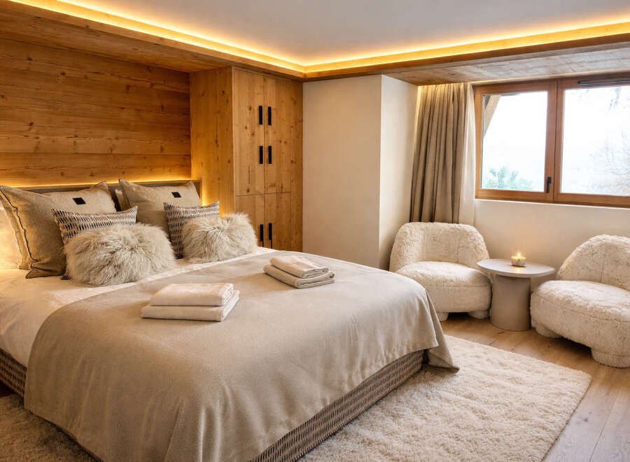 Experience luxury in this stunning bedroom featuring a cozy bed with plush pillows and a warm, inviting ambiance.