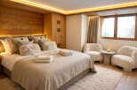 Experience luxury in this stunning bedroom featuring a cozy bed with plush pillows and a warm, inviting ambiance.