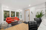 Step into modern living with this stylish property, featuring a vibrant red sofa and a cozy rug.