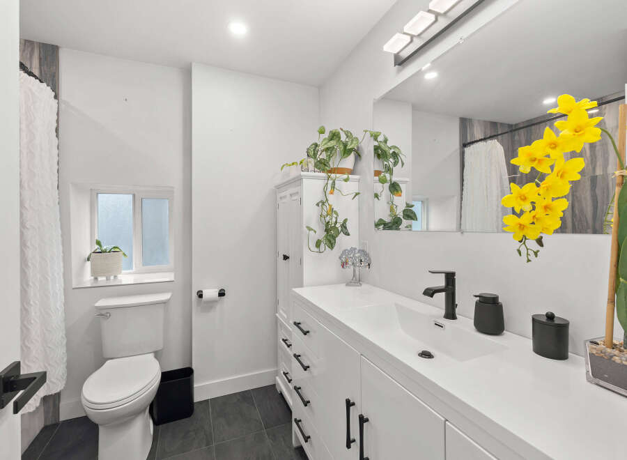 This stunning bathroom boasts a modern design with sleek white cabinetry and a spacious vanity.
