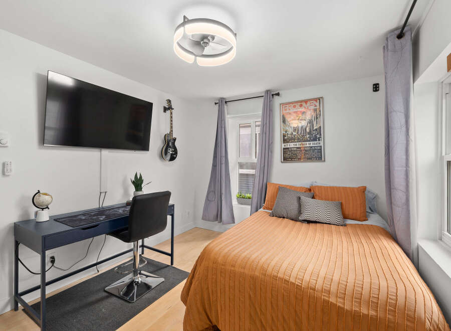 This stylish bedroom features a modern design with a mounted TV, a sleek desk, and a comfortable bed.