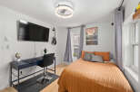 This stylish bedroom features a modern design with a mounted TV, a sleek desk, and a comfortable bed.
