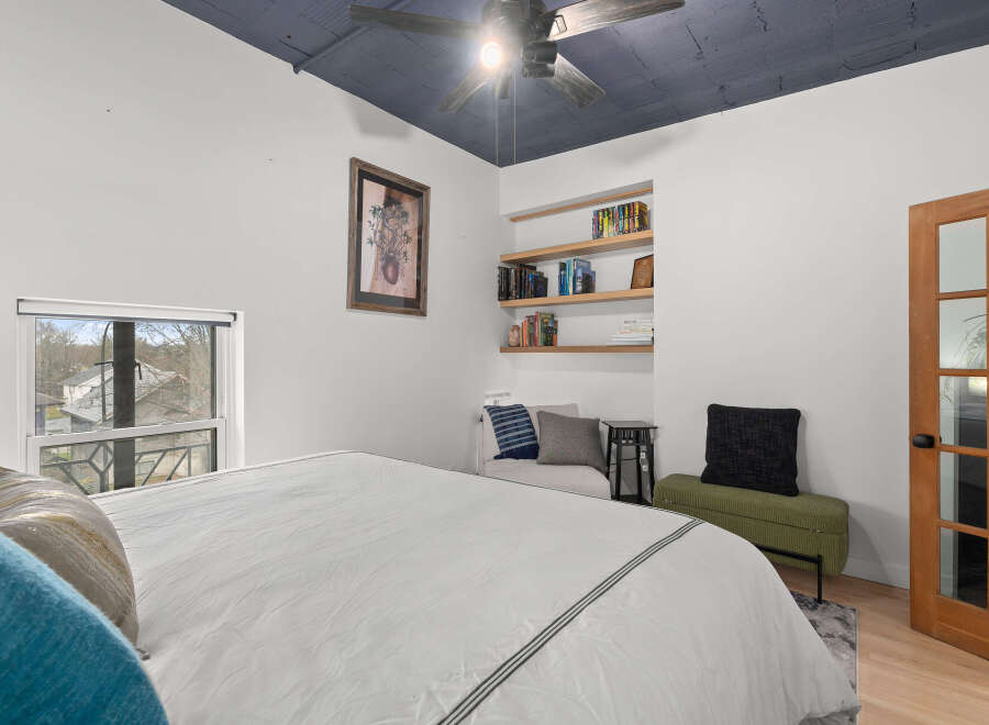 This stylish bedroom features a modern design with a unique blue ceiling and built-in shelving.