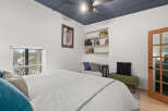 This stylish bedroom features a modern design with a unique blue ceiling and built-in shelving.
