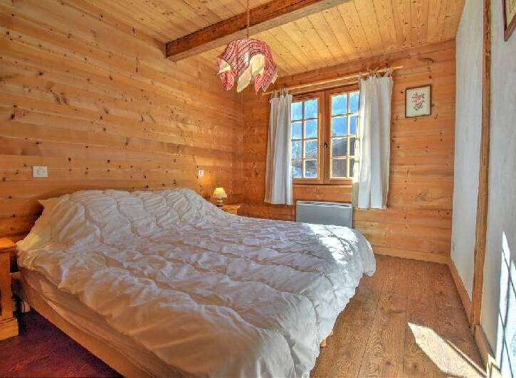 This charming bedroom features warm wooden walls and a cozy atmosphere, perfect for a relaxing retreat.