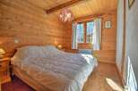 This charming bedroom features warm wooden walls and a cozy atmosphere, perfect for a relaxing retreat.