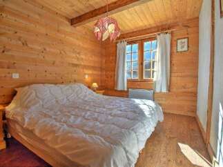 This charming bedroom features warm wooden walls and a cozy atmosphere, perfect for a relaxing retreat.