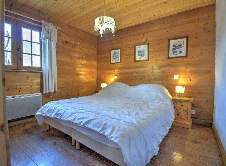 Cozy bedroom with wooden walls and flooring, creating a warm and inviting atmosphere.