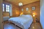 Cozy bedroom with wooden walls and flooring, creating a warm and inviting atmosphere.