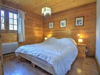Cozy bedroom with wooden walls and flooring, creating a warm and inviting atmosphere.