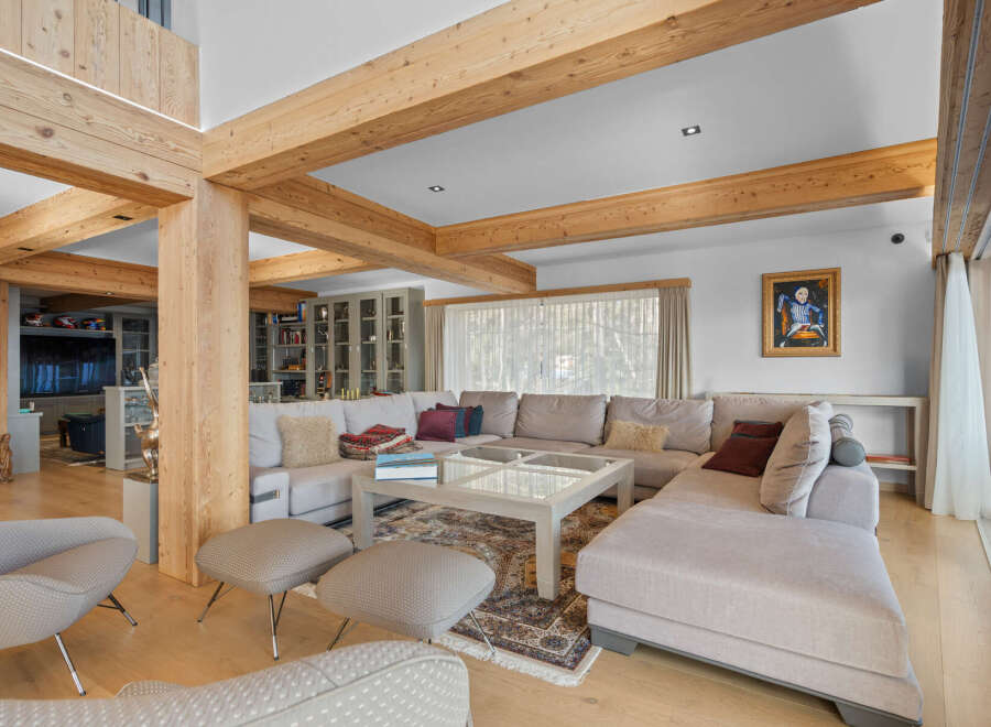 Experience luxury living in this stunning property featuring a spacious living area with exposed wooden beams and a comfortable sectional sofa.