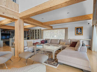 Experience luxury living in this stunning property featuring a spacious living area with exposed wooden beams and a comfortable sectional sofa.