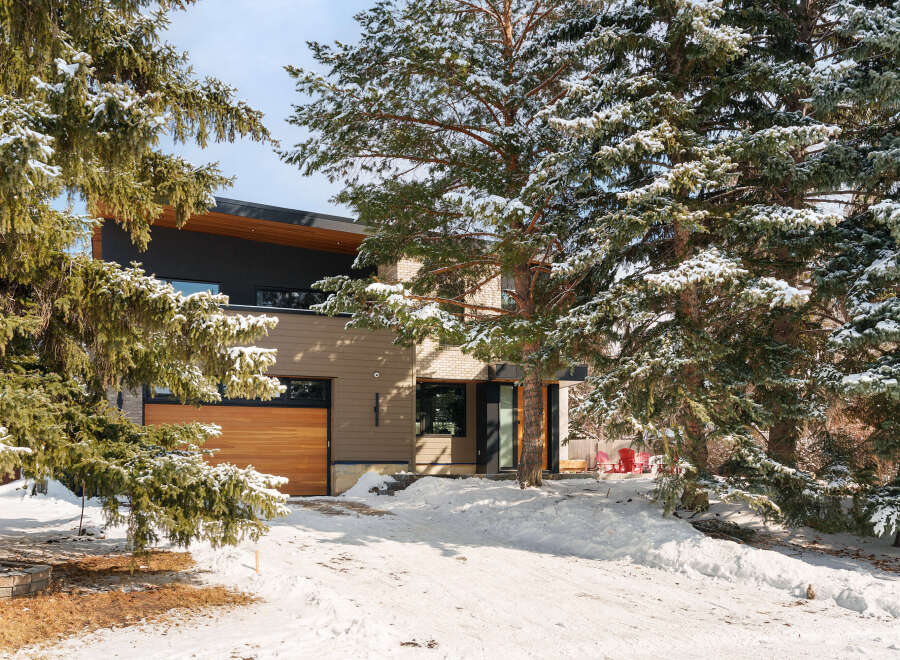 This stunning property boasts a modern design with a beautiful wooden garage door and a sleek, dark exterior.