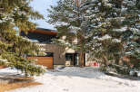 This stunning property boasts a modern design with a beautiful wooden garage door and a sleek, dark exterior.