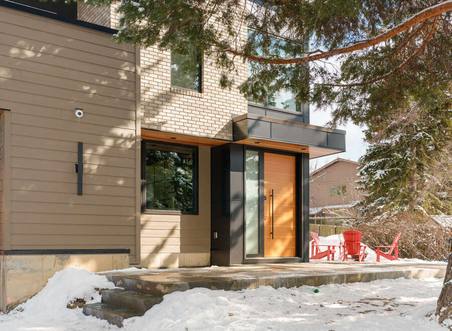 This stunning modern home boasts a sleek design with a warm, inviting wooden door and contemporary lines.