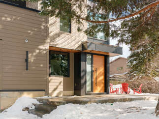 This stunning modern home boasts a sleek design with a warm, inviting wooden door and contemporary lines.