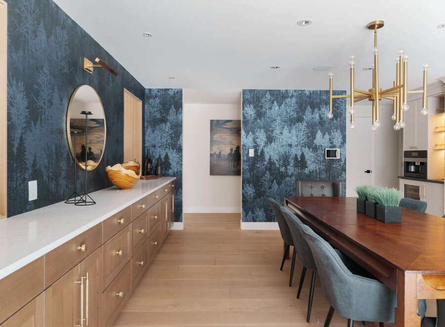 Step into luxury with this stunning dining room, featuring a striking accent wall with a unique forest-themed wallpaper.
