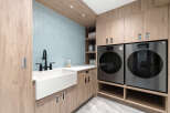 This stunning laundry room boasts a modern design with sleek cabinetry and a beautiful blue tile backsplash.