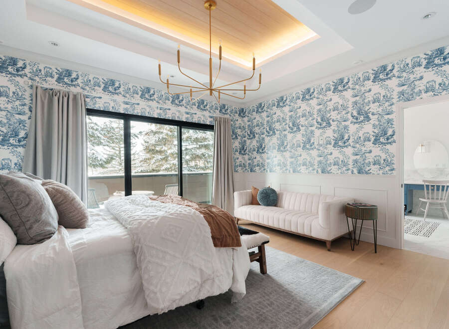Step into luxury with this stunning bedroom featuring elegant blue and white wallpaper and a modern chandelier.