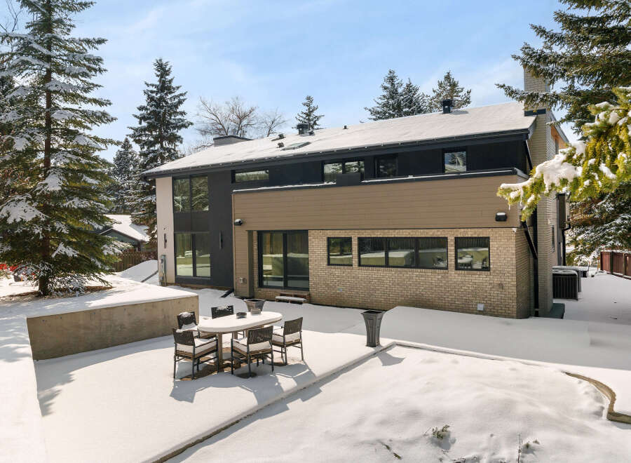 This stunning property boasts a modern design with a beautiful brick exterior and a snow-covered backyard.
