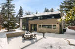 This stunning property boasts a modern design with a beautiful brick exterior and a snow-covered backyard.