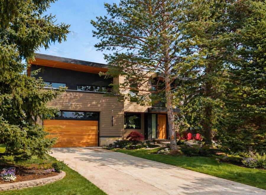 This stunning modern home boasts a sleek design with a beautiful wooden garage door and exterior.