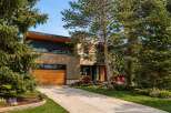 This stunning modern home boasts a sleek design with a beautiful wooden garage door and exterior.