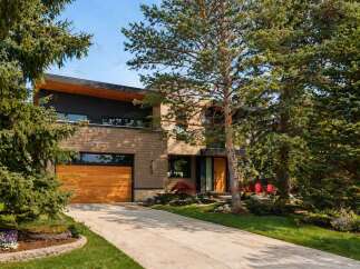 This stunning modern home boasts a sleek design with a beautiful wooden garage door and exterior.