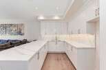 This stunning kitchen boasts a modern design with sleek white cabinetry and elegant marble countertops.