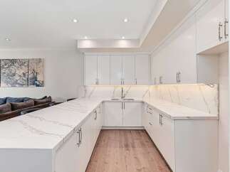 This stunning kitchen boasts a modern design with sleek white cabinetry and elegant marble countertops.