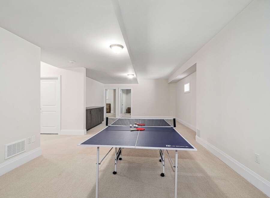 This spacious recreation room features a ping pong table, perfect for entertaining and family fun.