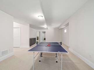 This spacious recreation room features a ping pong table, perfect for entertaining and family fun.