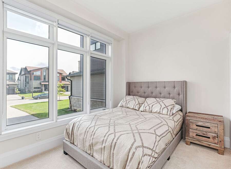This stunning bedroom features a large window that offers plenty of natural light and a beautiful view of the neighborhood.