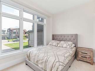 This stunning bedroom features a large window that offers plenty of natural light and a beautiful view of the neighborhood.