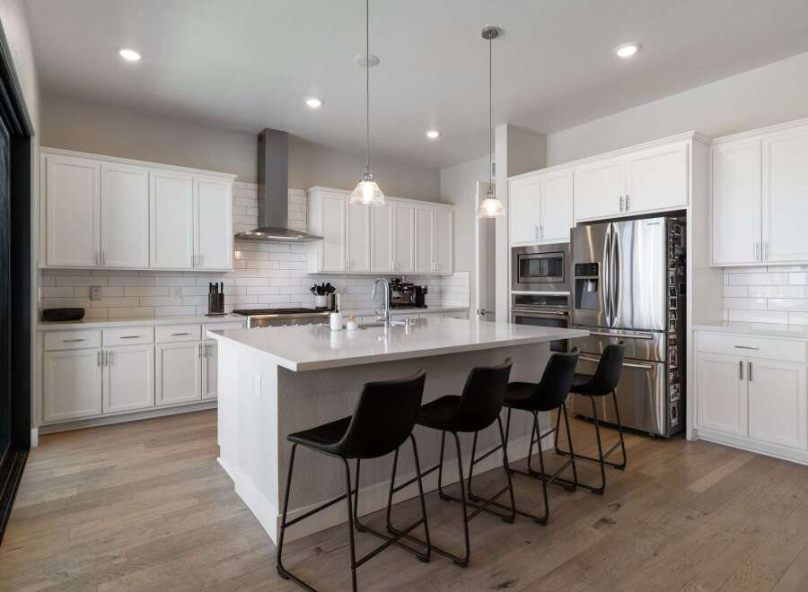This stunning kitchen boasts a modern design with sleek white cabinetry and a spacious island, perfect for both cooking and entertaining.