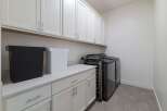 This stunning laundry room boasts ample storage with its sleek white cabinets and a pristine countertop.