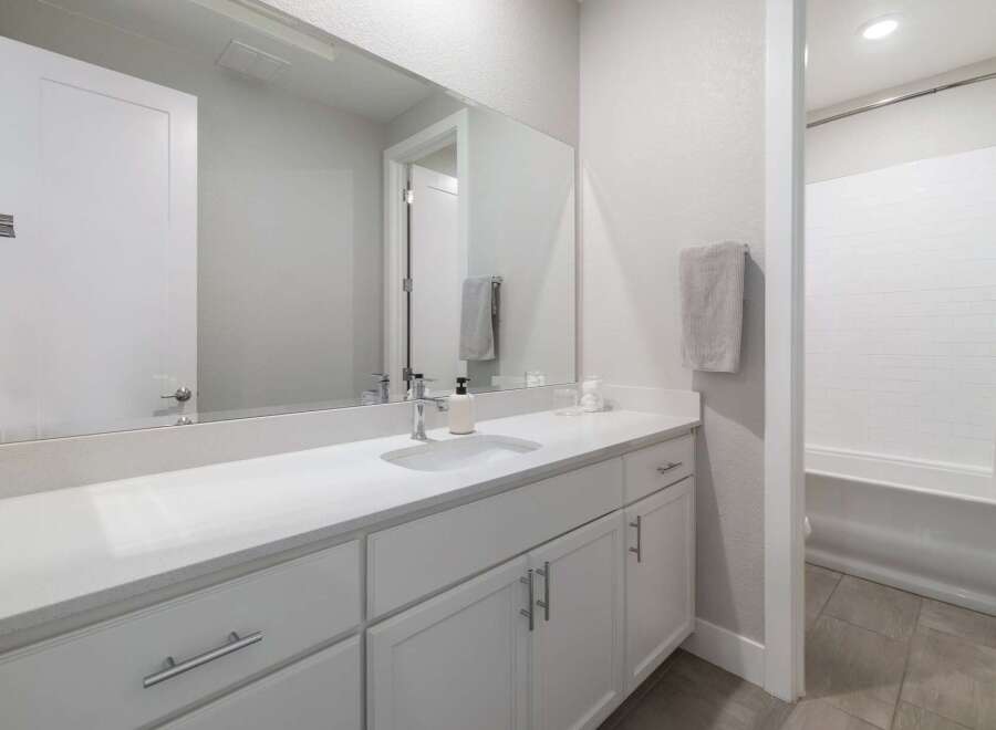 This modern bathroom features a sleek white vanity with ample storage and a large mirror.