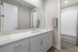 This modern bathroom features a sleek white vanity with ample storage and a large mirror.