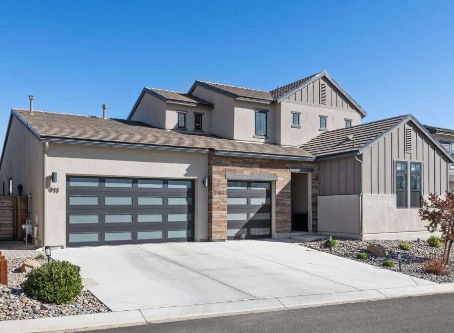 This stunning modern home boasts a sleek design with a spacious driveway and a beautifully landscaped front yard.