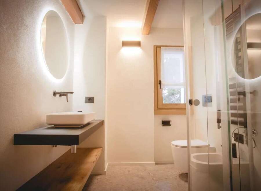 This modern bathroom features a sleek design with a floating vanity and a stylish oval mirror with integrated lighting.