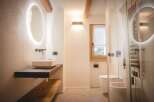 This modern bathroom features a sleek design with a floating vanity and a stylish oval mirror with integrated lighting.