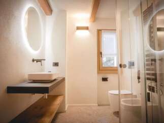 This modern bathroom features a sleek design with a floating vanity and a stylish oval mirror with integrated lighting.