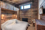 Experience rustic charm in this cozy bedroom, featuring stunning wood paneling and a warm, inviting atmosphere.