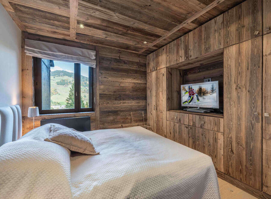 This stunning bedroom showcases rustic elegance with its wood-paneled walls and ceiling, creating a warm and inviting atmosphere.