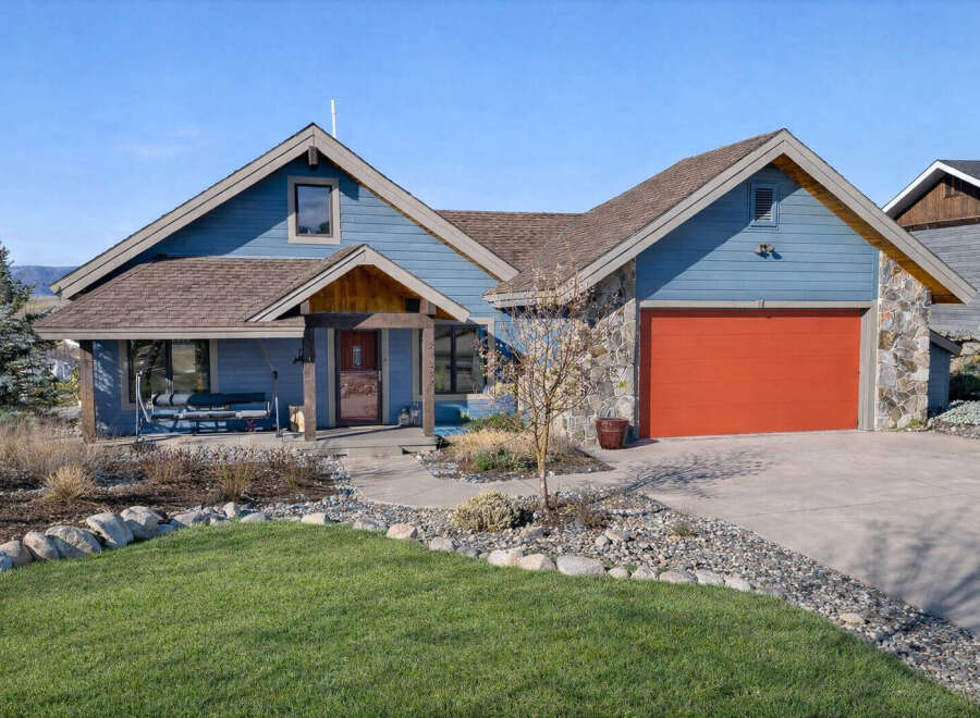This stunning home boasts a beautiful exterior with a vibrant red garage door and a charming stone facade.