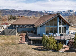 This stunning property boasts a beautiful blue exterior and a spacious deck, perfect for enjoying the breathtaking mountain views.