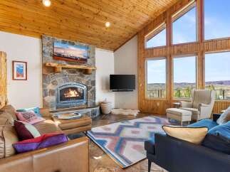 Experience the warmth and charm of this stunning living room, featuring a cozy fireplace and a rustic stone facade.