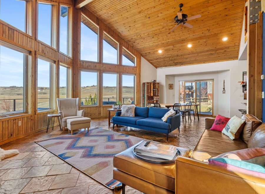 This stunning property boasts a spacious living area with soaring ceilings and expansive windows, offering breathtaking views of the surrounding landscape.