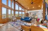 This stunning property boasts a spacious living area with soaring ceilings and expansive windows, offering breathtaking views of the surrounding landscape.