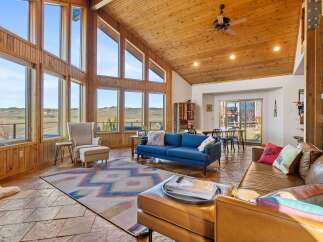 This stunning property boasts a spacious living area with soaring ceilings and expansive windows, offering breathtaking views of the surrounding landscape.
